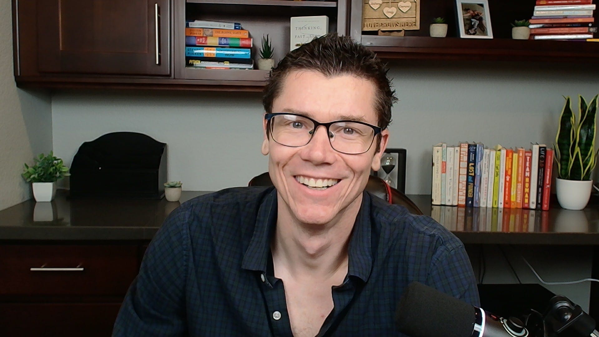 Digital marketing expert TJ Robertson smiling in a home office studio with bookshelves, guest on Counsel Cast.