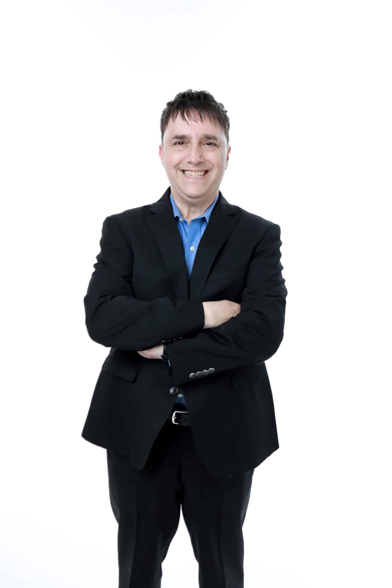Professional studio portrait of fractional CMO and author Neal Schaffer smiling with arms crossed against a white background, guest on Counsel Cast.