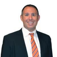 Professional headshot of Adam Hersh, founder and principal of Blue Chip Law, wearing a dark suit and orange striped tie.
