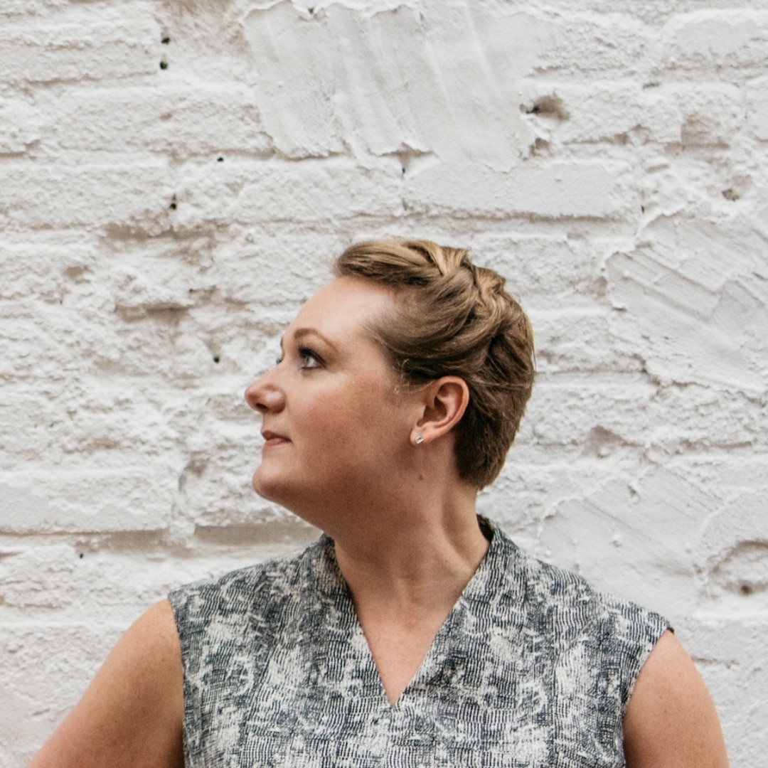 Profile headshot of Rachel Allen looking upward against a painted white brick wall, guest on Counsel Cast.