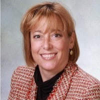 Professional headshot of Andrea Cannavina smiling in a red and white patterned jacket.