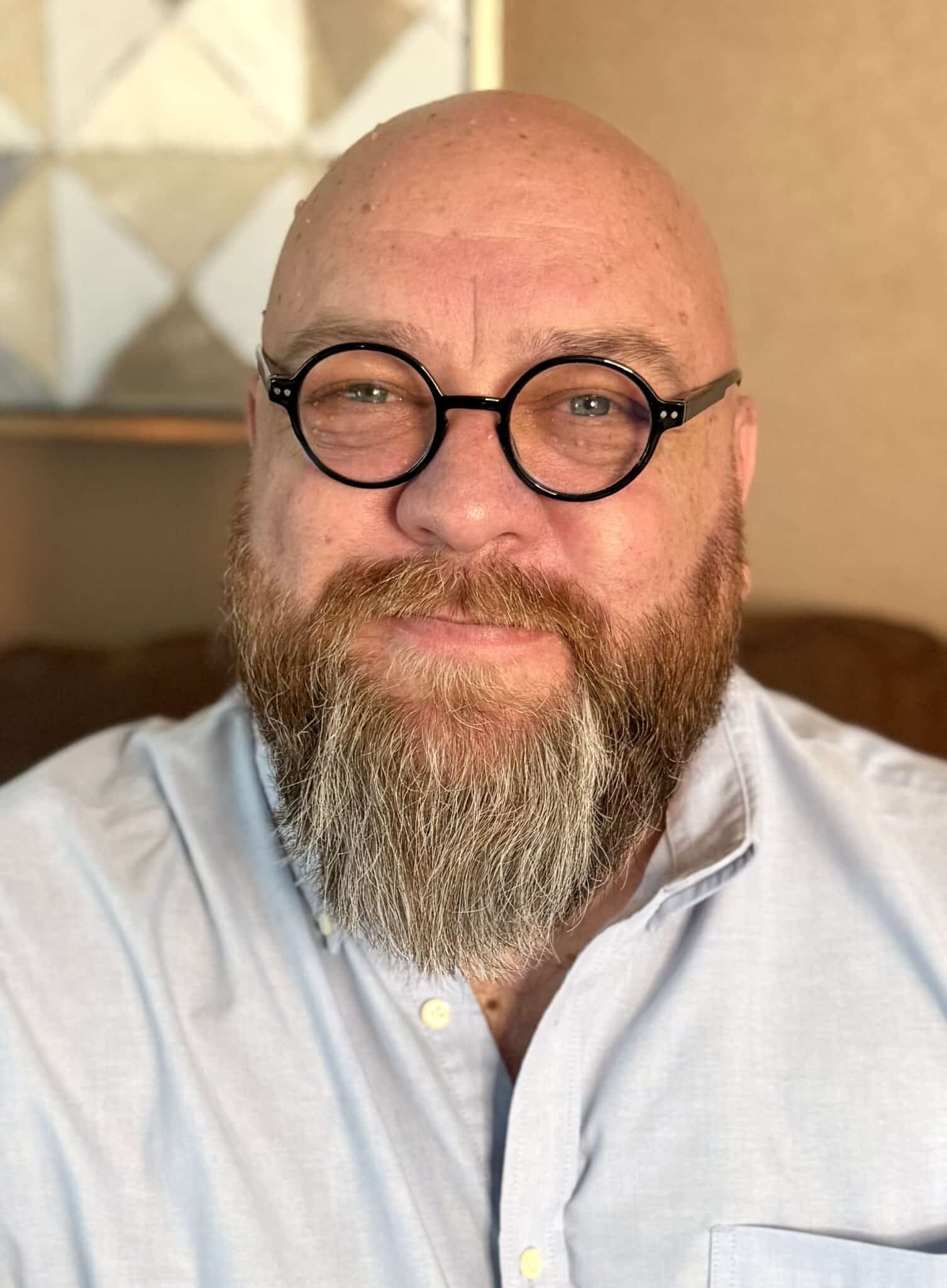 Close-up studio headshot of Doug Vannatta wearing round black glasses and a light blue shirt, guest on Counsel Cast.